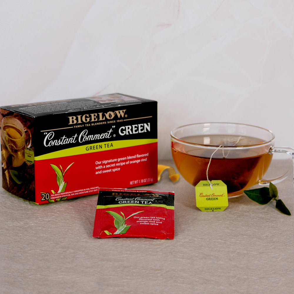 Bigelow Constant Comment Green tea packaging with a cup of tea on a neutral background