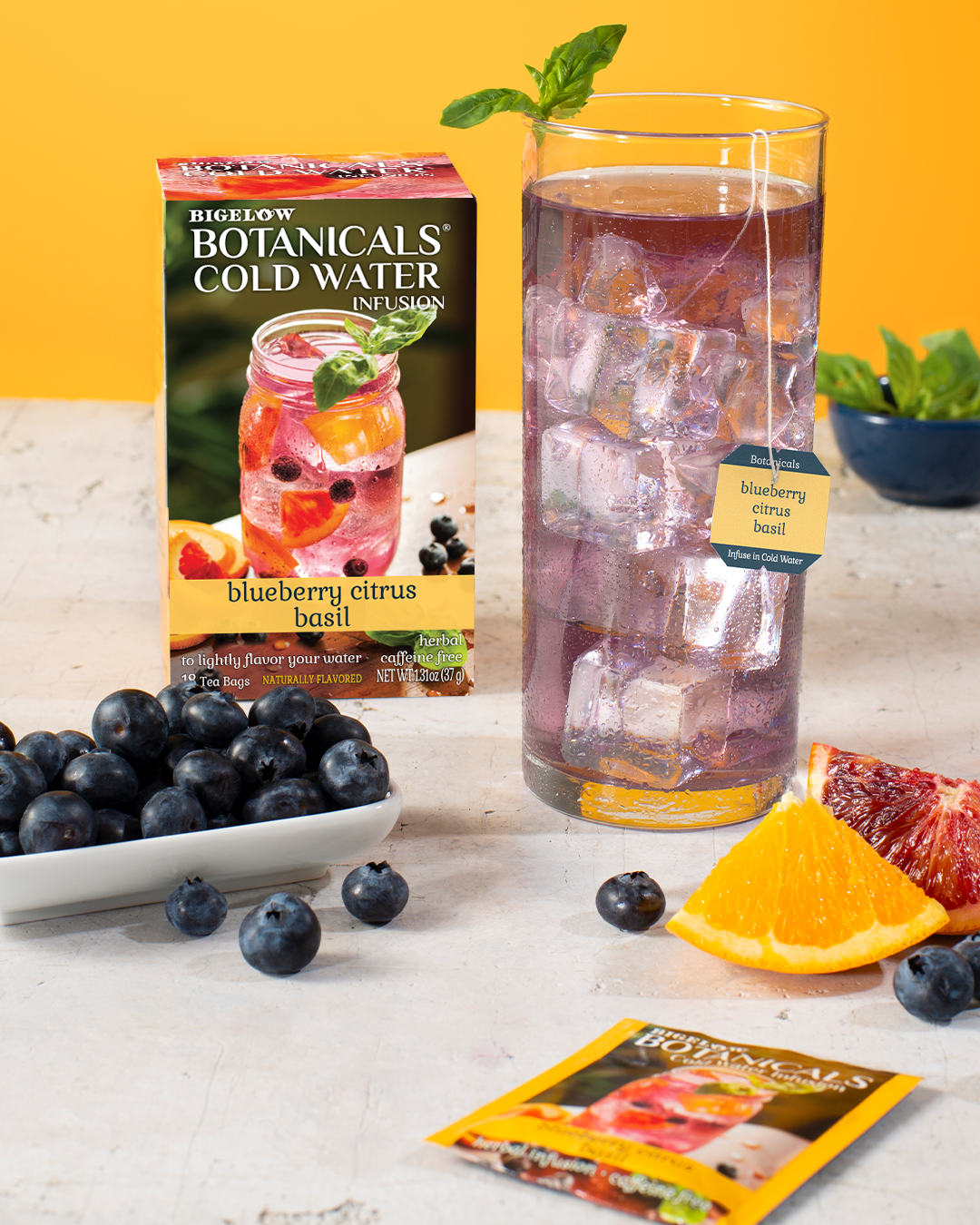 Mason jar filled with Blueberry Citrus Basil Cold Water Infusion with tea box and foil