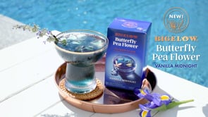 Bigelow Butterfly Pea Flower Vanilla Midnight Herbal Tea Box with glass of blue tea on ice