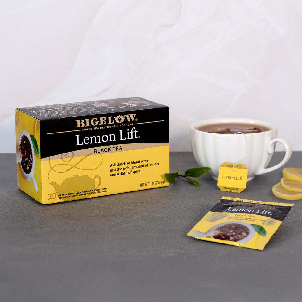 Bigelow Lemon Lift Black Tea packaging with a cup of tea on a gray surface.