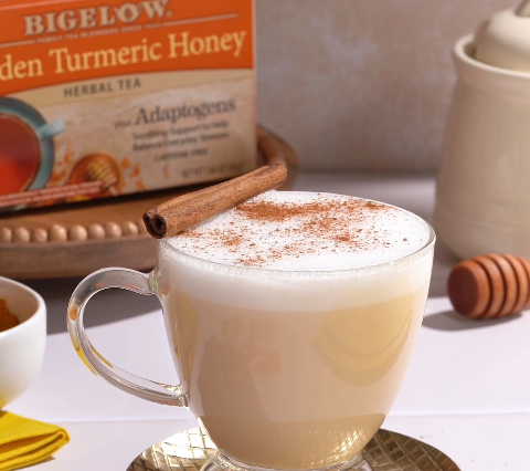 glass cup filled with Golden Turmeric Honey Tea with turmeric in bowl with honey dipper
