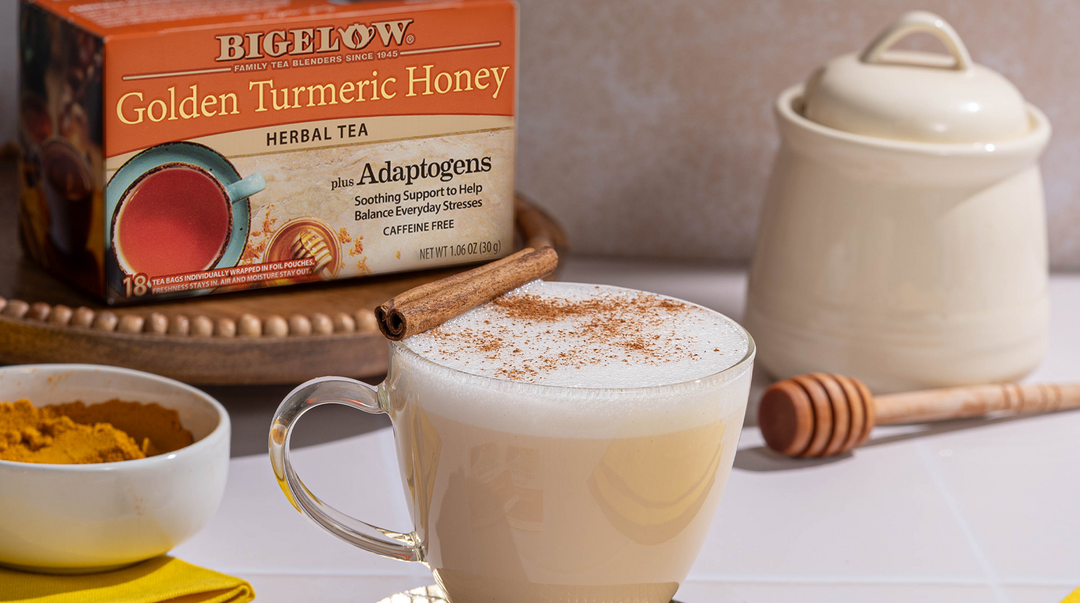 glass cup filled with Golden Turmeric Honey Tea with turmeric in bowl with honey dipper