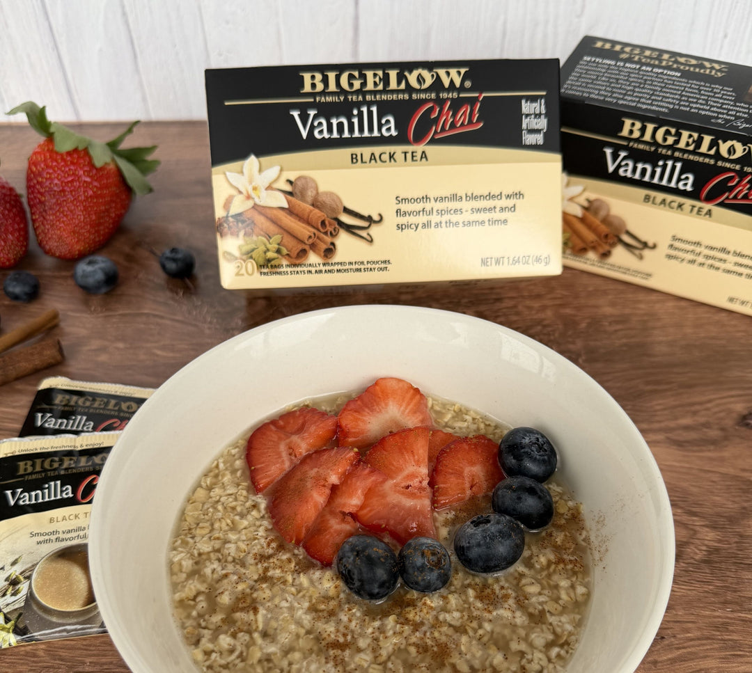 white bowl of oatmeal with berries and 2 boxes of Bigelow Vanilla Chai 
