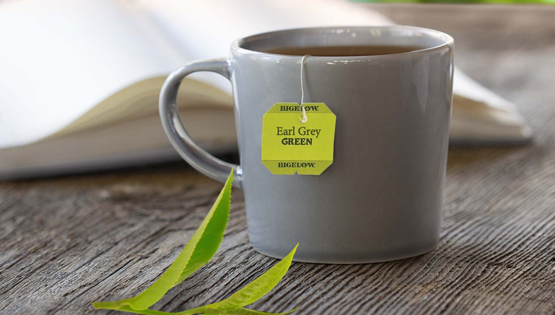 gray mug of tea on wood table with open book