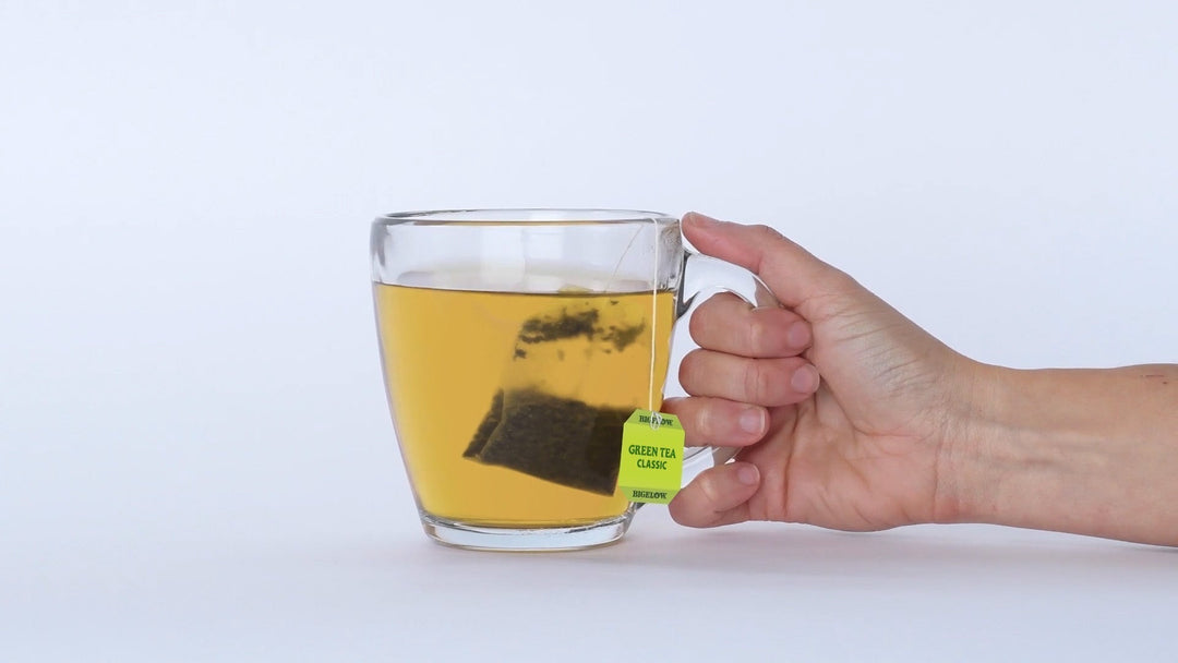 Hand holding glass cup of green tea