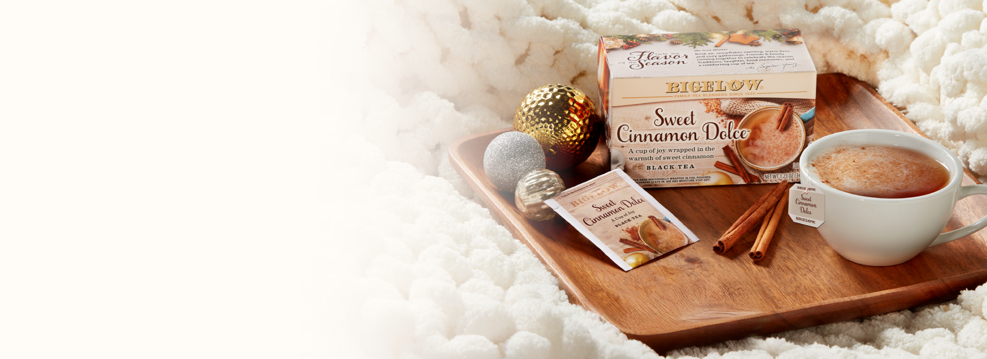 Wooden tray with a cup of coffee, cinnamon sticks, and a box of Sweet Cinnamon Dots on a soft white background.