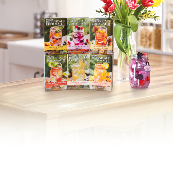 Packaging of Botanica Cold Water drinks on a kitchen counter with a vase of flowers.