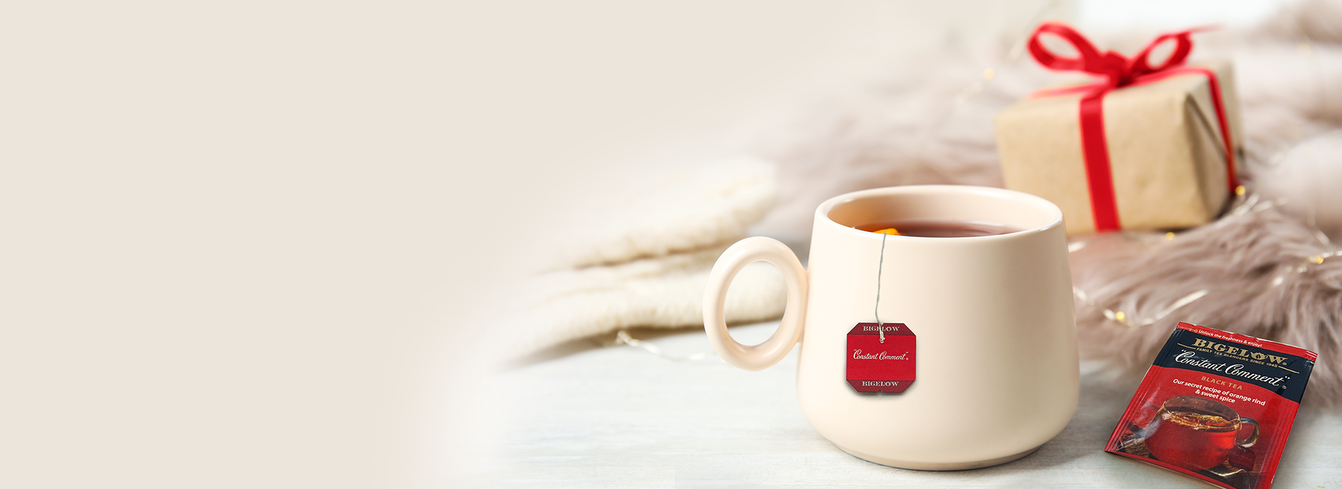 White mug with a red teabag label, gift box, and tea package on a soft white background