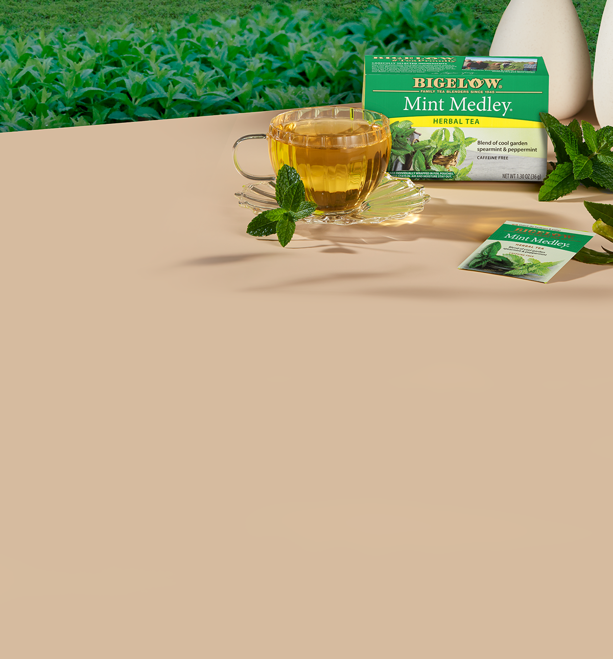 Bigelow Mint Medley tea packaging with a cup of tea and mint leaves on a beige surface.