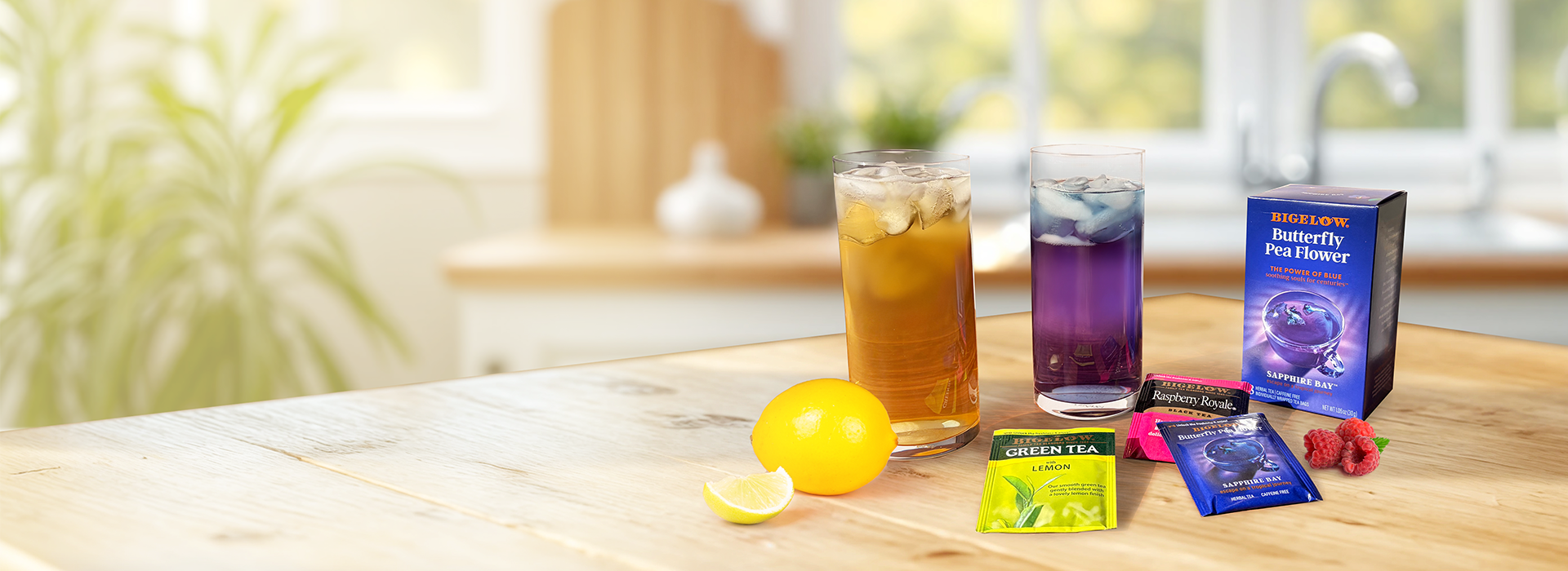 Tea bags, lemon, and glasses of iced tea on a wooden table with a blurred background