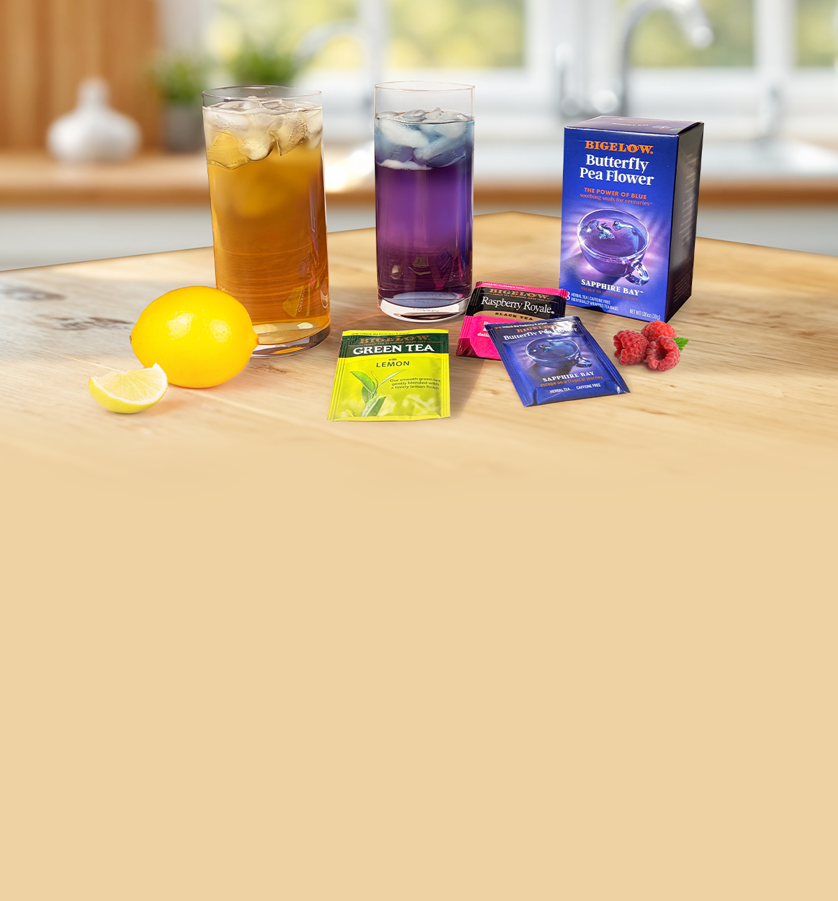 Two glasses of iced tea with lemon slices, tea bags, and a box on a wooden surface.