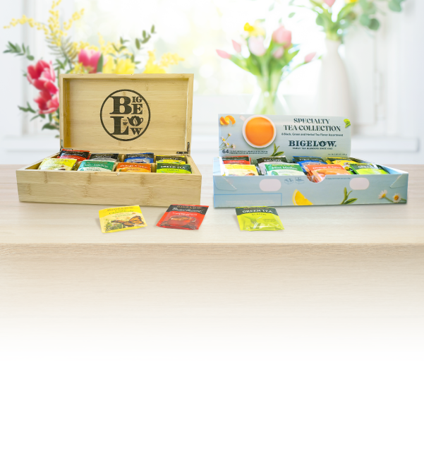 Tea packages from Bigelow and other brands on a table with a wooden box labeled 'Be Below'.