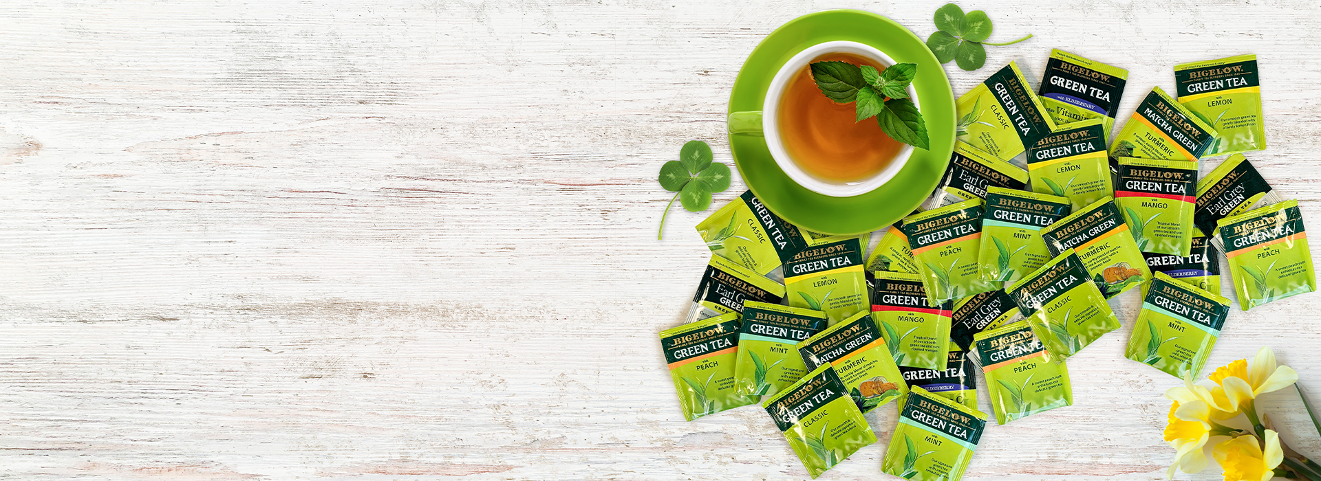 Green tea packages with a cup of tea on a wooden surface