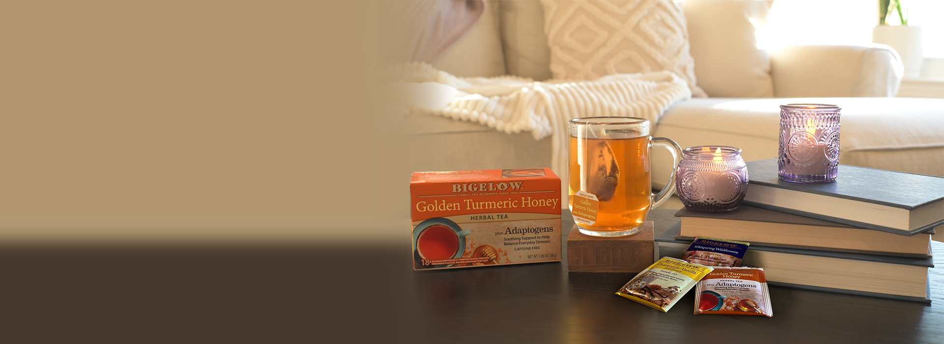 Bigelow Golden Turmeric Tea box and glass mug of tea on table with candles and books in a living room setting