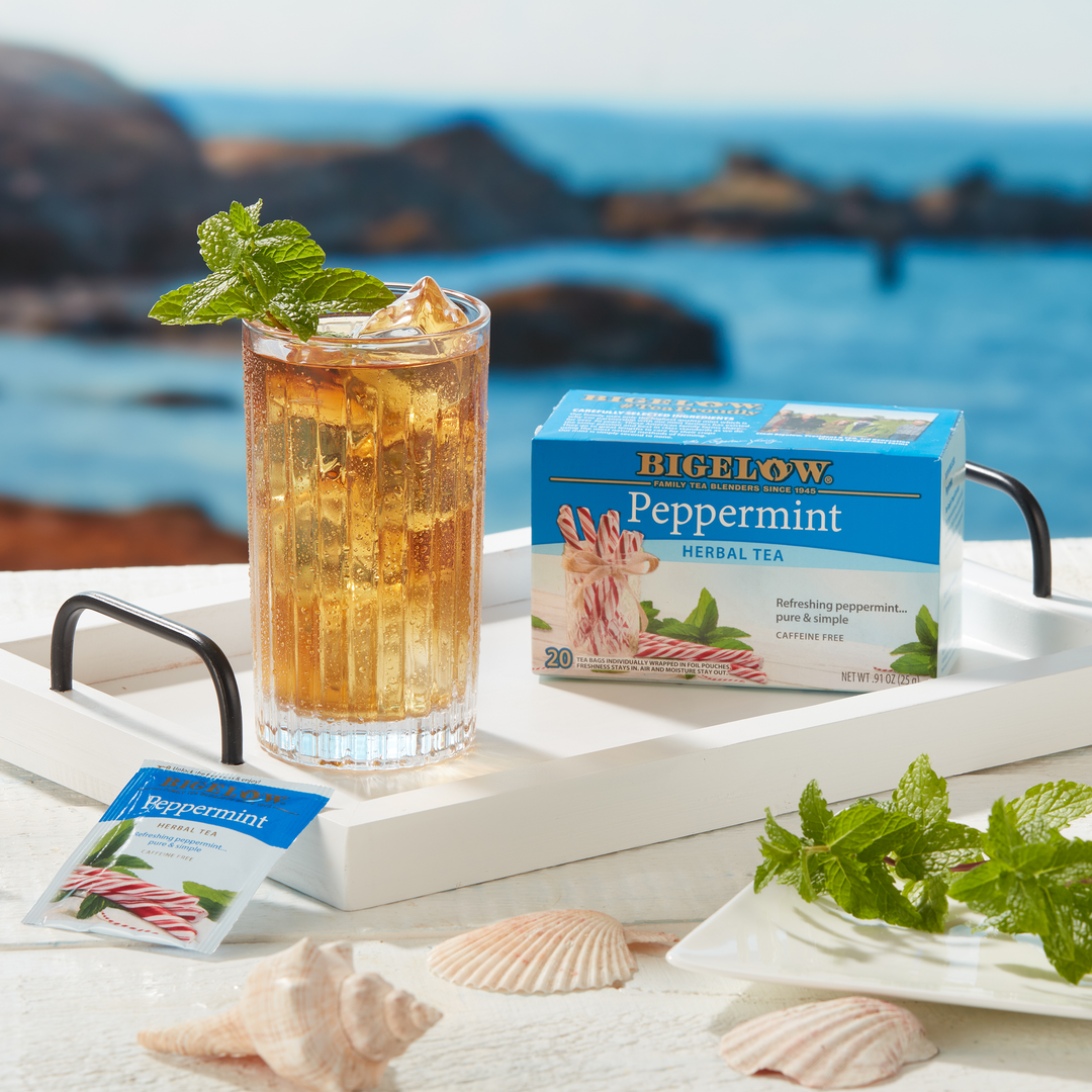 Glass of Peppermint Herbal Tea Iced on white tray with water background