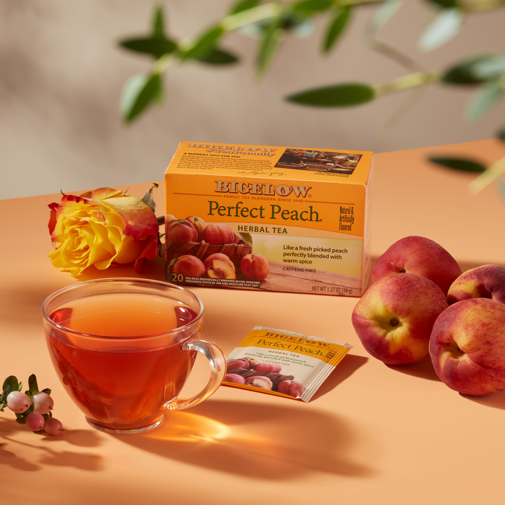 Glass cup of  Perfect Peach Herbal Tea on peach cloth with peach ingredients