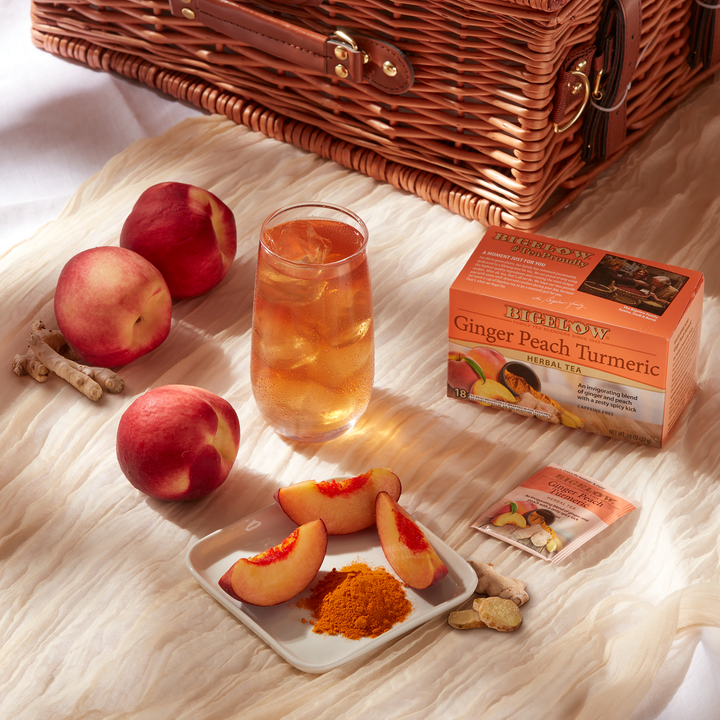 Glass of Ginger Peach Turmeric Herbal Tea Iced with picnic basket and peaches