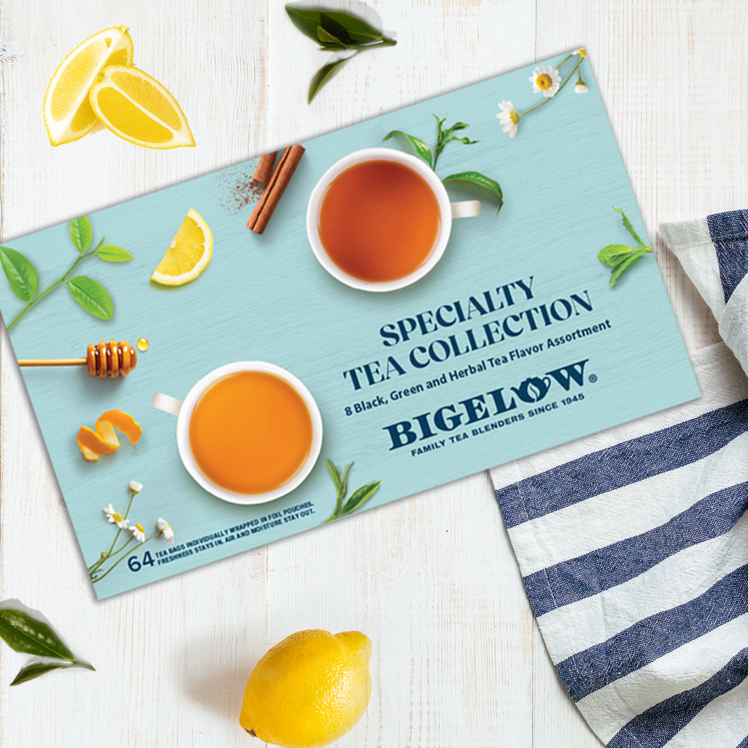 Closed Bigelow tea box with tea cups and lemon slices on a white surface