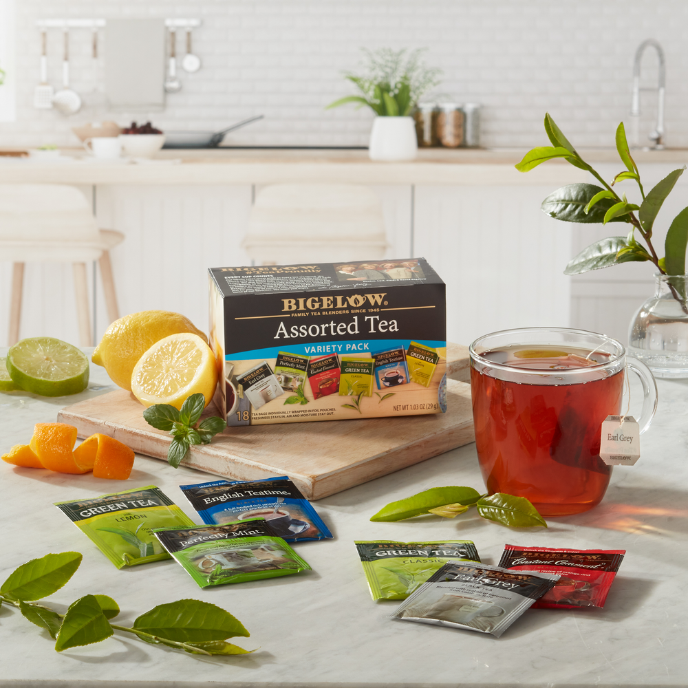 Box of Bigelow Assorted Tea Variety with glass mug and foil packets in kitchen setting