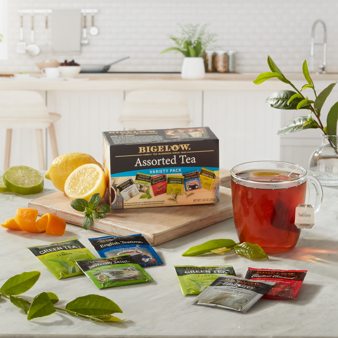 Box of Bigelow Assorted Tea Variety with glass mug and foil packets in kitchen setting