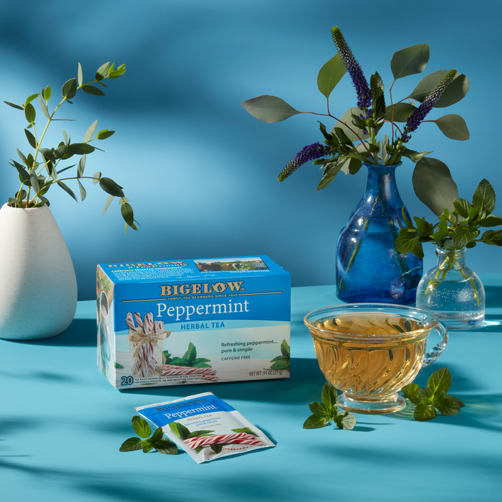 Glass mug of Peppermint Herbal Tea on blue cloth with blue background