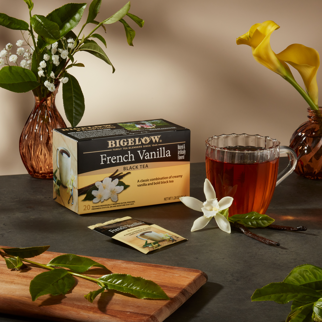 Glass mug of French Vanilla Tea on gray countertop with flowers and vases