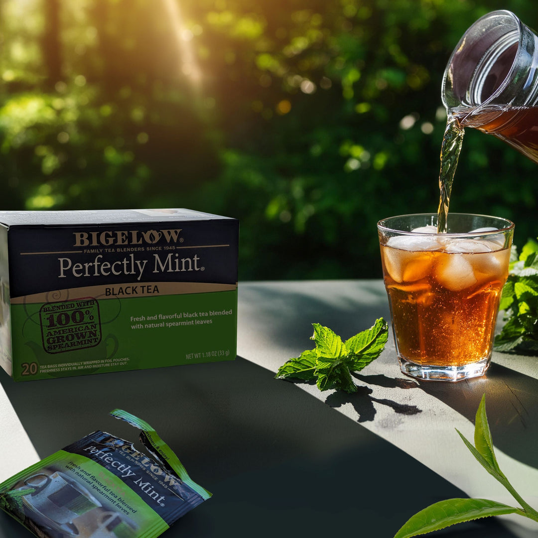 Outside setting with pouring Perfectly Mint Black Tea into glass with ice and box of tea