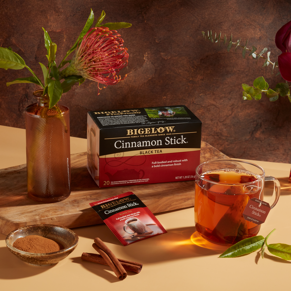 Cup of Cinnamon Stick with box and  foil and cinnamon stick on tabletop with 2 vases with flowers