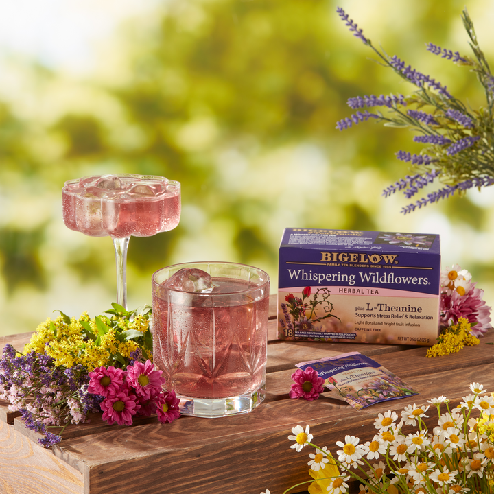 2 glasses with ice and Whispering Wildflowers Plus L-Theanine Herbal Tea with box and foil packet with flowers