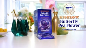 Blue drink in glass mug with box of Butterfly Pea Flower Sapphire Bay tea on white counter