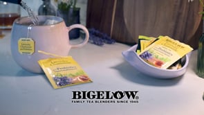 tea mug on white table with Bigelow logo and Bigelow Lavender Chamomile Tea foil packets in white bowl