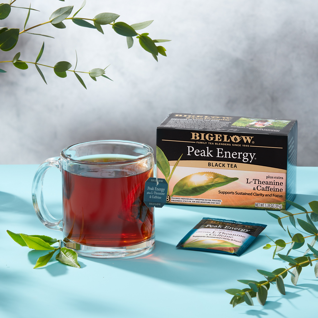 Glass cup  of Peak Energy with box, with ingredients and blue and white teapot on blue cloth with printed background