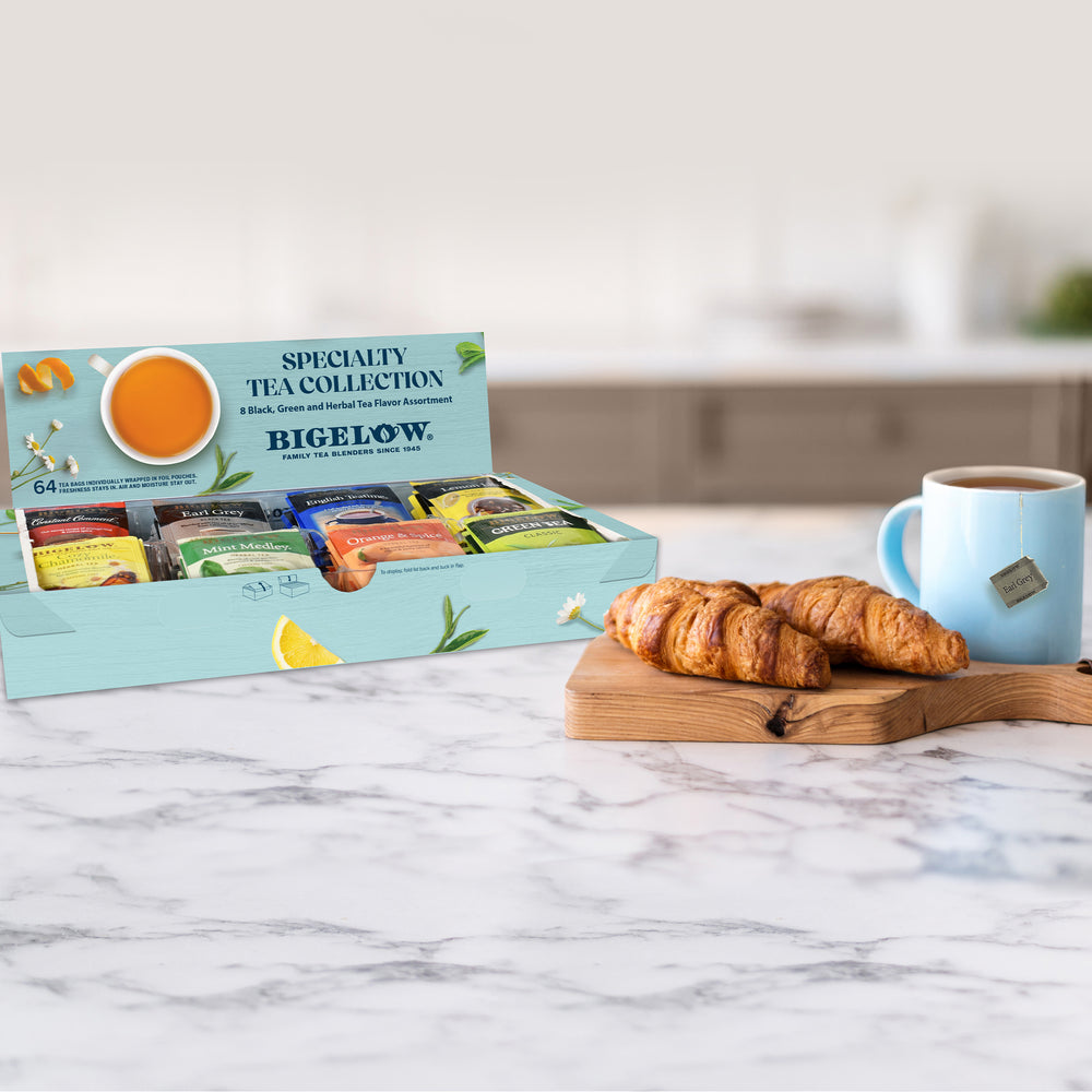 Bigelow tea collection box with croissants and a mug on a marble surface