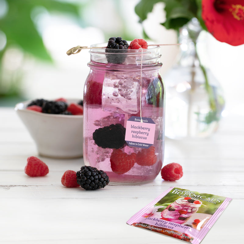 Mason jar filled with Blackberry Raspberry Hibiscus Cold Water Infusion with tea box and foil